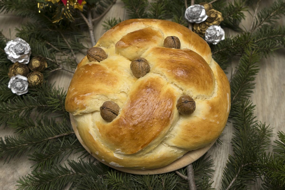 Round Christopsomo bread decorated with a dough cross and walnuts