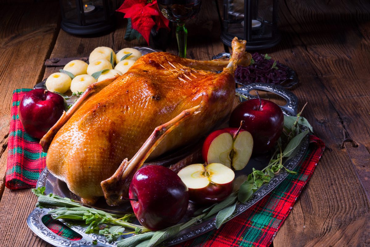 Whole roast goose with red apples on a festive platter
