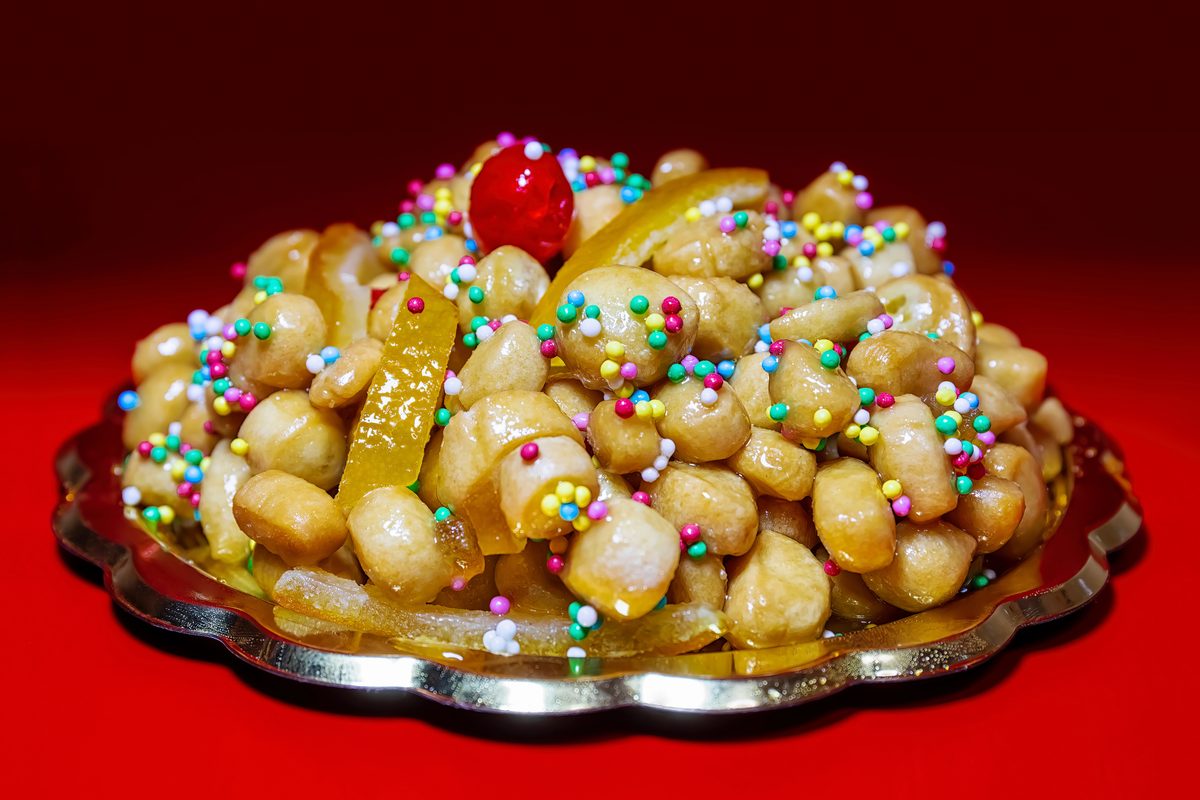 Struffoli, small fried dough balls glazed with honey and colored sprinkles, on a platter
