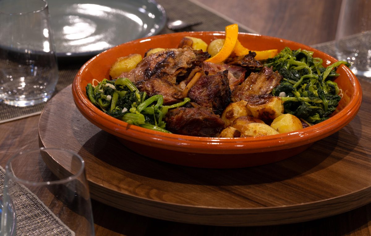 Cabrito assado, roast kid goat with potatoes in a clay dish
