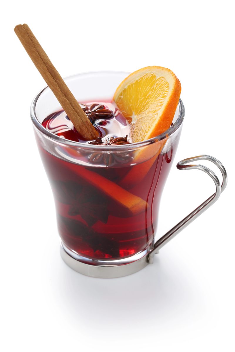 Glass mug of vinho quente mulled wine with orange and a cinnamon stick