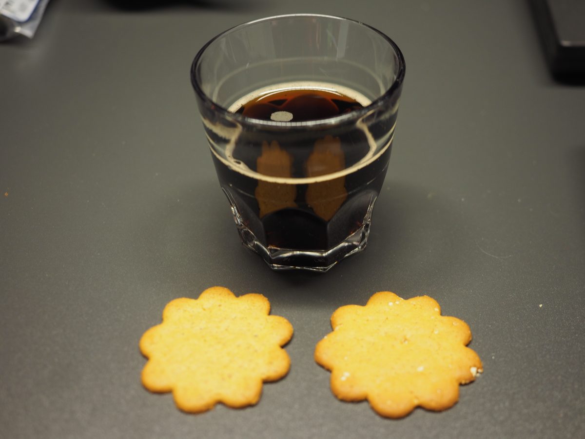Dark Swedish julmust Christmas soda in a glass beside ginger cookies