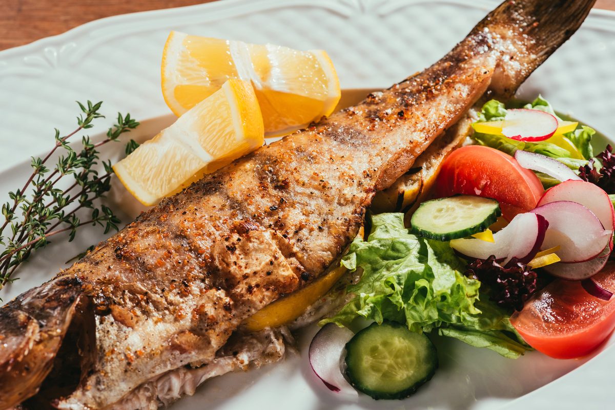 Whole baked fish with lemon and herbs, served with salad