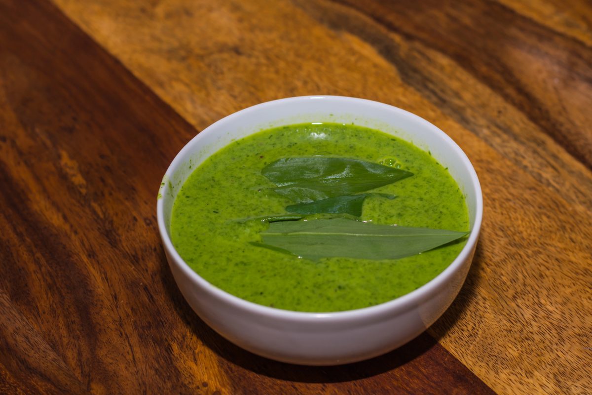 Bowl of bright green wild garlic soup with wild garlic leaves