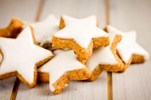 Zimtsterne, star-shaped cinnamon cookies with white meringue icing, on a wooden table