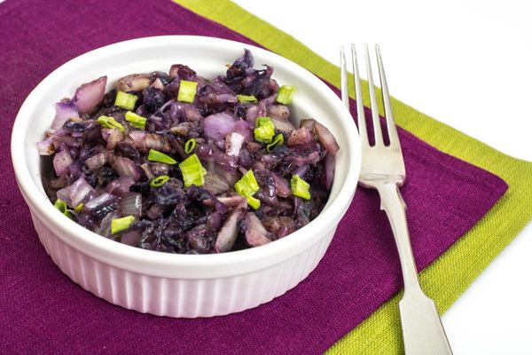 Braised red cabbage in a white bowl, with a fork and napkin