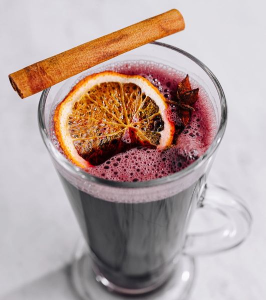 Glass of mulled wine garnished with an orange slice and a cinnamon stick