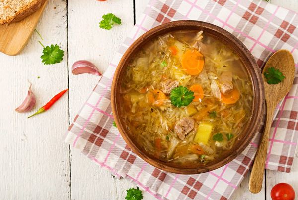 Kapustnica, sauerkraut soup with sausage and mushrooms, in a bowl