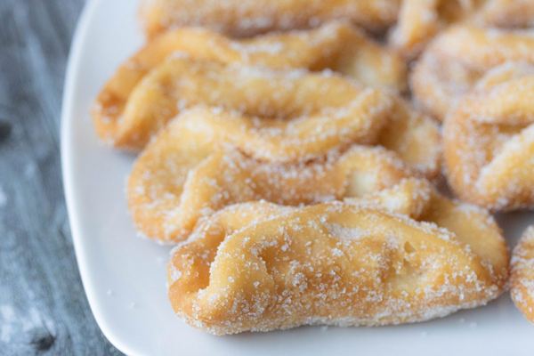 Sugar-coated pestiños, Andalusian honey fritters, on a white plate