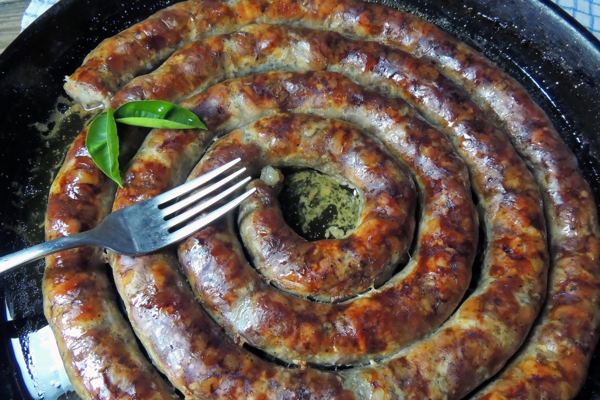 Coil of roasted white sausage in a pan