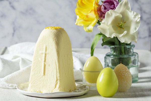 Sweet cheese paska with a cross pattern, next to Easter eggs and flowers
