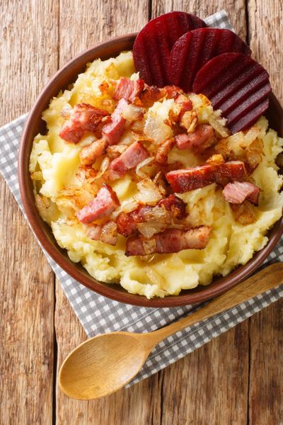 Mashed potatoes topped with fried bacon and onions, with pickled beets